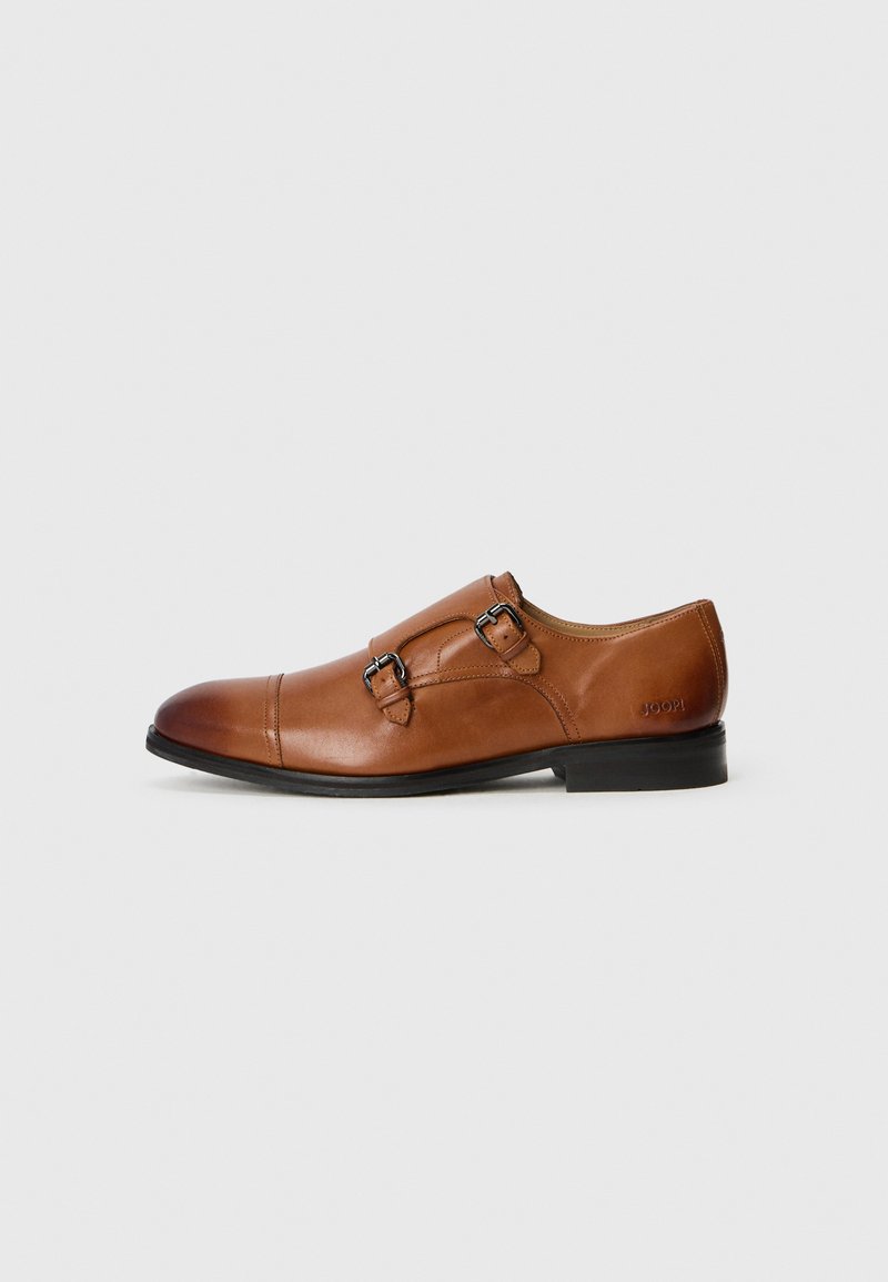 Zapato de vestir de cuero marrón con doble hebilla, punta redondeada y textura suave. Presenta una silueta elegante con un tacón negro bajo.