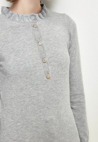 Pull en gris avec col côtelé, doté d'une patte de boutonnage avec quatre boutons dorés et des manches longues, fabriqué en tissu doux et texturé.