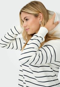 Biała bluza z kapturem w granatowe paski, o miękkiej strukturze, z regulowanym kapturem i ściągaczami na mankietach. Zauważalny detal: kaptur odciągnięty.