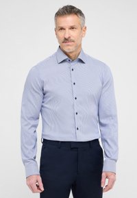 Camicia da uomo azzurro chiaro a maniche lunghe con sottili righe bianche, colletto con bottoni e bottoni a contrasto blu scuro. Tessuto morbido, vestibilità sagomata.