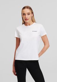 Bílý bavlněný tričko s kulatým výstřihem a krátkými rukávy, na levé straně hrudi s malým černým logem "KARL LAGERFELD".