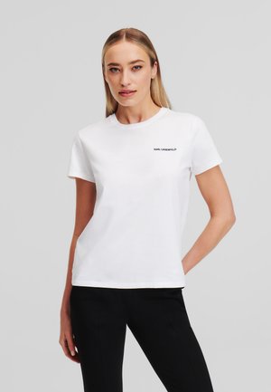 T-shirt bianca in cotone con scollo rotondo e maniche corte, caratterizzata da un piccolo logo nero "KARL LAGERFELD" sul lato sinistro del petto.
