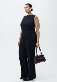 Čierny bezrú štop a široké nohavice z pleteného materiálu, v kombinácii s burgundskou štruktúrovanou kabelkou so zdvojenými uchami a zlatými akcentmi.