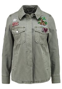 Oliivivihreä käyttötakki, jossa on kaksi rintataskua, brodattu palmu, sydän ja teksti "COOL". Puuvillamateriaali ja rento istuvuus.