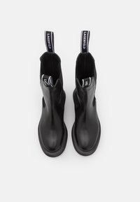 Black ankle boots made of smooth leather, featuring a rounded toe, elastic side panels, and pull tabs with brand logo accents on top.