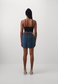 Koptatott, kék farmer miniszoknya ezüst szegecsekkel, rugalmas derékrésszel és két hátsó zsebbel. Fekete camisole top.