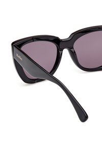 Occhiali da sole neri a forma di occhio di gatto con lenti scure, finitura lucida e design elegante. Presentano il marchio sul braccio laterale.