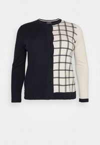 Button-up cardigan with one solid black half and one cream half featuring black grid lines, long sleeves, and a round neckline.