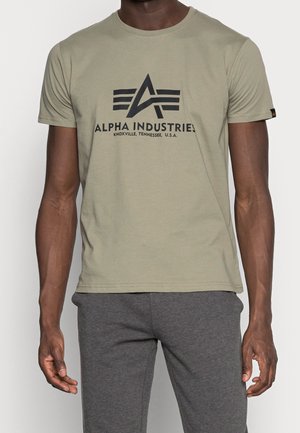 T-shirt di cotone verde oliva con maniche corte, scollo rotondo e stampa nera con il logo "ALPHA INDUSTRIES" sul petto.