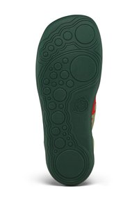 Green rubber outsole with textured grip patterns, featuring circular and wavy designs, accompanied by a small logo detail.