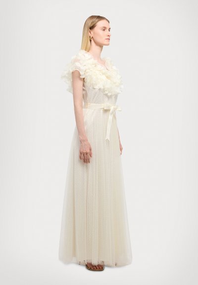Long white dress with a textured polka dot design, ruffled floral neckline, and a satin belt at the waist. Soft and flowing silhouette.