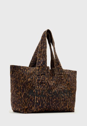 Sac fourre-tout imprimé léopard brun et noir avec deux poignées et un texte noir subtil sur le tissu, sur fond gris.