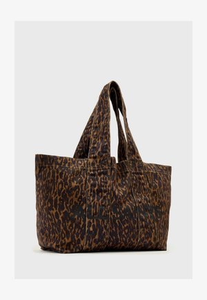 Sac fourre-tout imprimé léopard brun et noir avec deux poignées et un texte noir subtil sur le tissu, sur fond gris.
