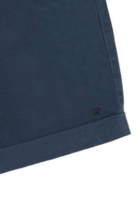 Pantalones cortos de algodón azul marino con dobladillo enrollado, que presentan un logo de tijeras bordado en la parte inferior de la pierna. Textura suave, ajuste entallado.