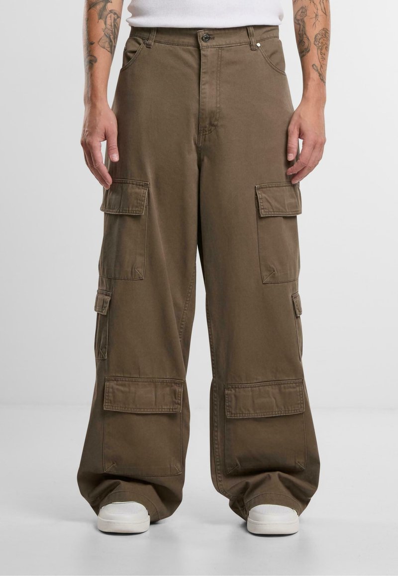 Pantalones cargo marrones con un corte holgado, que presentan múltiples bolsillos frontales y laterales, fabricados con una tela resistente y con costuras detalladas.