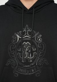 Czarna bluza z kapturem z błyszczącą, ciemnoszarą ozdobną grafiką z inicjałami "RC" oraz napisem "cavalli UOMO" na środku, z kapturem ze sznurkiem.