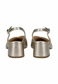 Sandales à talons blocs dorées métalliques avec une bride arrière et une boucle réglable. Texture lisse et design à bout rond. Semelle en caoutchouc.