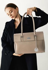 Borsa a mano strutturata beige in pelle texturizzata, con hardware argentato e un ciondolo a forma di orologio staccabile. Caratterizzata da doppi manici e chiusura a pattina.