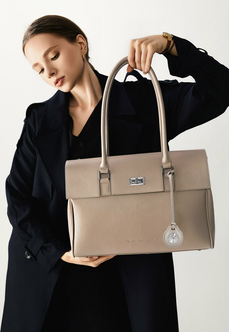 Borsa a mano strutturata beige in pelle texturizzata, con hardware argentato e un ciondolo a forma di orologio staccabile. Caratterizzata da doppi manici e chiusura a pattina.