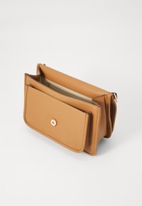 Borsa in pelle di colore talpa con chiusura a pulsante dorato, dotata di una tasca con zip e un compartimento aperto con una fodera di colore chiaro.