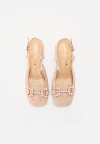 Roze zamšaste slingback čevlje s kvadratnim prstom. Imajo okrasni trak z očitnimi dragulji. Gladke notranje sole. Nastavljiv gleženjski trak.