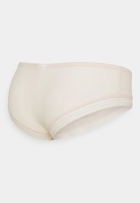 Shorts beige realizzati in un tessuto morbido, con una cintura ampia bordata di pizzo e una leggera texture. Sides senza cuciture per maggiore comfort.