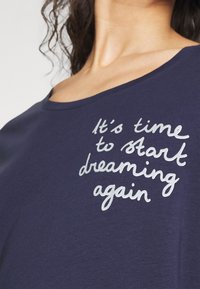 Marinblå T-shirt i mjukt material med avslappnad halsringning och silvertryck som säger "Det är dags att börja drömma igen."