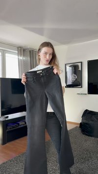 Jean noir en denim évasé avec une taille mi-haute, un design à cinq poches et une fermeture par bouton. Texture lisse et légère extensibilité.