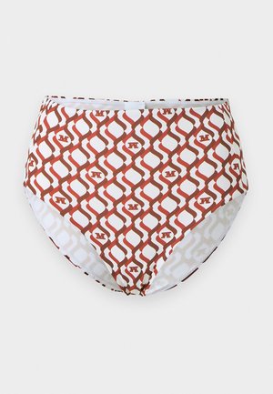 Γυναίκα που στέκεται, φοράει τοπ μαγιό σε σκουριασμένο χρώμα, σλιπ μαγιό με υψηλή μέση και μαύρα σανδάλια σε λευκό φόντο.