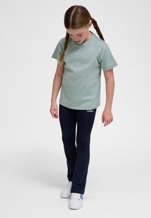 Lys grøn bomulds T-shirt med korte ærmer og logo. Komplementeret af slim-fit navy leggings og hvide sneakers. Enkel, afslappet design.