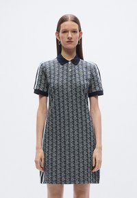 Póló ruha tengerészkék és világoskék színekben, geometrikus mintával, gallérral és rövid ujjakkal, kontrasztos oldalsávokkal.