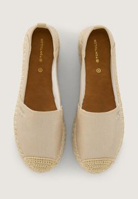 Espadrilles en toile beige avec une semelle en jute tissée. Design sans lacets avec une texture lisse et des détails de couture subtils. Logo doré sur la semelle intérieure.