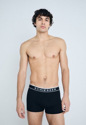 Schwarze Boxershorts aus weichem Material mit einem weißen elastischen Bund, auf dem der Markenname "SCHIESSER" in Großbuchstaben steht.