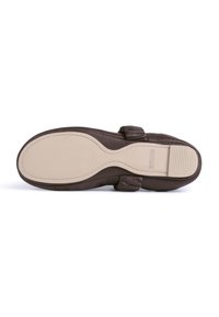 Suela de zapato de cuero marrón con una textura suave, con una suela exterior de goma beige, costuras sutiles y un diseño curvado con un pequeño tacón.