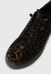 Black and gold leopard print sneaker with textured suede material, black laces, and circular metal eyelets. Flat rubber sole.
