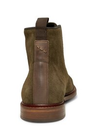Stivale alla caviglia in suede marrone con un pannello posteriore in pelle marrone liscia, punta arrotondata e tacco in legno basso, dotato di un'asola in tessuto per una facile calzata.