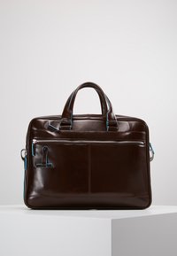 Borsa in pelle marrone con dettagli blu, dotata di doppie maniglie, una tasca frontale con zip e una forma rettangolare elegante. Texture liscia, finitura lucida.