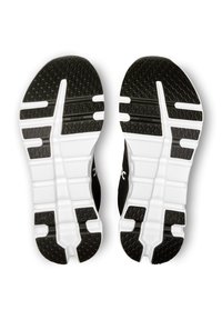 Semelles de chaussures de sport noires avec des motifs de grip en caoutchouc texturé ; bandeau intermédiaire blanc ; conçues pour le confort et l'adhérence lors des activités.