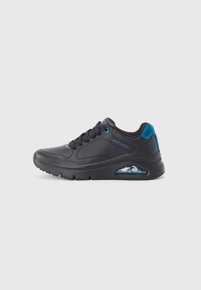 Chaussure de sport noire en matériau synthétique, avec un design basse, des perforations décoratives, des accents bleus et une unité de coussinage d'air visible.