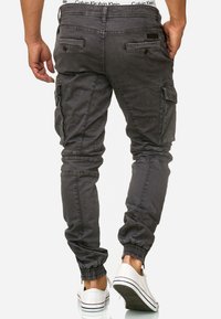 Cargo joggers in dark gray denim, featuring elastic cuffs, multiple pockets, and a Calvin Klein logo waistband. Textured fabric finish.