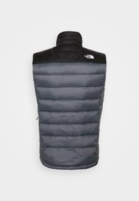 Veste sans manches matelassée en gris foncé avec empiècement d'épaule noir, col montant, design matelassé horizontal et logo blanc "The North Face" à l'arrière à droite.