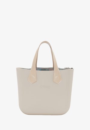 Bolso tote beige hecho de material suave, con dos asas complementarias y un forro interior con patrón. Detalle de cierre con cremallera visible.