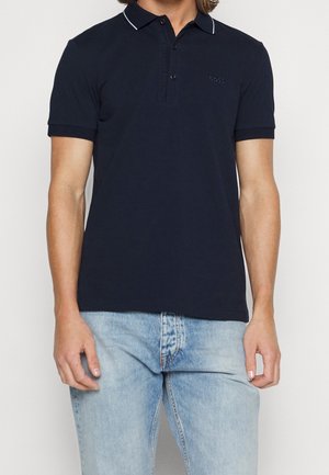 Polo bleu marine avec col et accents blancs, en coton doux. Présente une patte à trois boutons et un petit logo sur la poitrine.