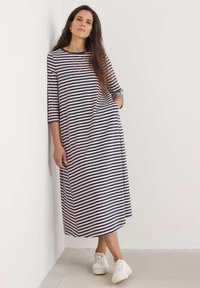 Pruhované maxi šaty v tmavě modré a světle růžové bavlně, se třičtvrtinovými rukávy, bočními kapsami, volným střihem a bílými teniskami.
