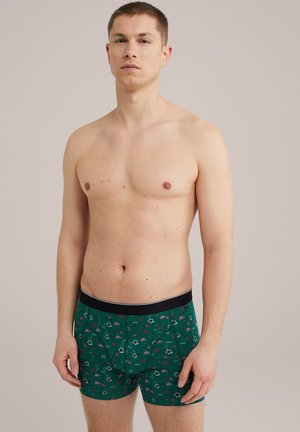 Zöld mintás boxer nadrág fekete derékkal, piros és fehér árnyalatú virágos mintázattal. Puha anyag, közepes hosszúságú.