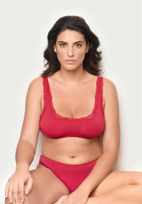 Röd lingerie-set som består av en bralette i tank-stil med spetskant och matchande högskurna trosor, tillverkade av mjukt, stretchigt material.