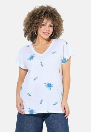 T-shirt bianco con scollatura a V, decorato con ricami floreali blu e dettagli verdi. Maniche corte e vestibilità comoda, realizzato in tessuto leggero e testurizzato.