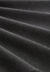 Tejido de un gris oscuro texturizado con un patrón de tejido visible, que muestra múltiples pliegues y una superficie suave y densa.