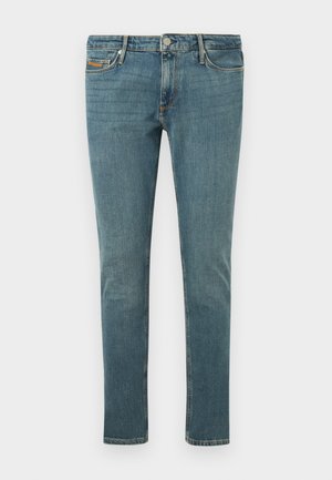 Jean slim bleu avec cinq poches, fermeture à boutons et légère décoloration sur les cuisses et les genoux sur un fond clair uni.