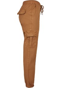 Pantalon cargo marron avec taille élastique et bas de jambes resserrés, doté de poches avant, latérales et arrière avec rabats et détails à cordon de serrage.